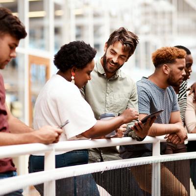 An office team engaged in discussion while standing by a railing.