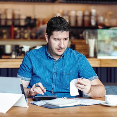 A male restaurant owner calculating business bills.