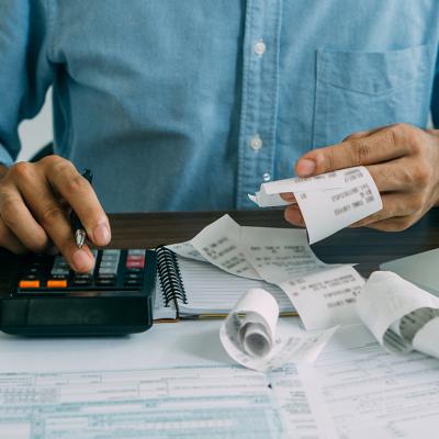 A man computes bills using a calculator.