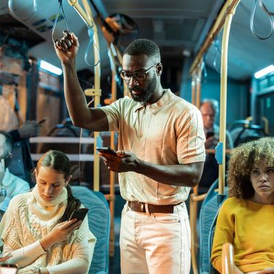 A young black man standing in a crowded bus at night.