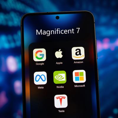 A smartphone's app folder named 'Magnificent 7' and displays app icons of Google, Apple, Amazon, Meta, Nvidia, Microsoft, and Tesla.