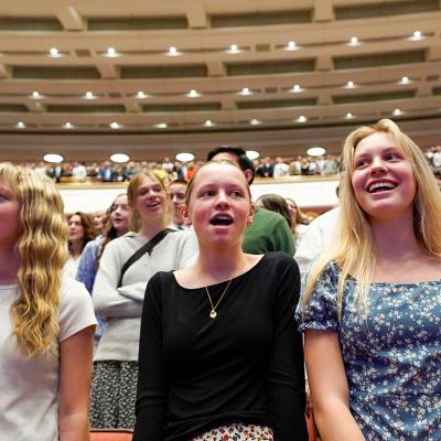 Low angle view of young women singing a hymn during a session of General Conference of The Church of Jesus Christ of Latter-day Saints in April 2025. 