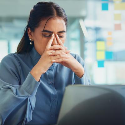 A frustrated young woman in front of her laptop at work.