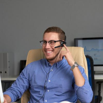 A young businessman in a home office smiling while talking to a client.