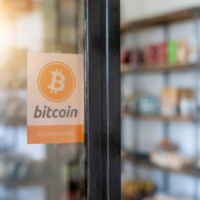 A entrance door sign showing 'Bitcoin (is) accepted here)'.