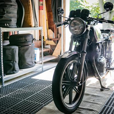 A black vintage motorcycle stored in an open garage.