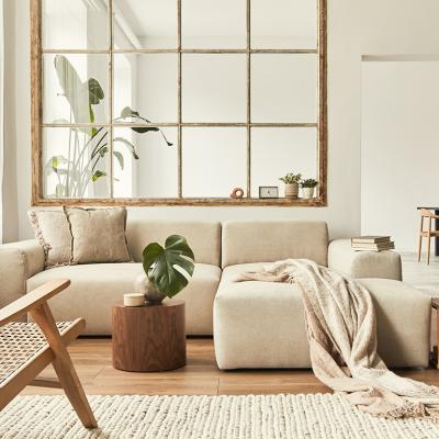 Interior of a modern living room with a modular sofa, decorated with beige and wooden motifs.