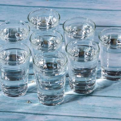 Eight glasses of water on a wooden table.