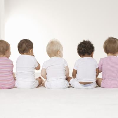 Rear view of five babies sitting on the floor.