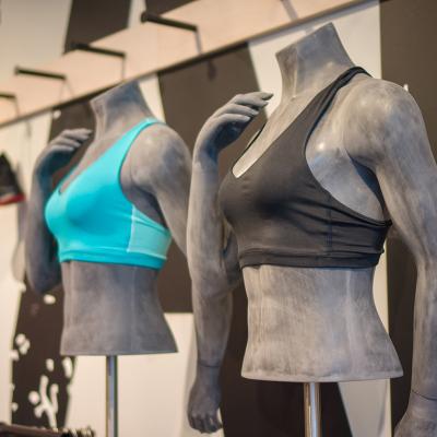 Different colors of women's sports bra displayed on torso mannequins at a sports clothing store.
