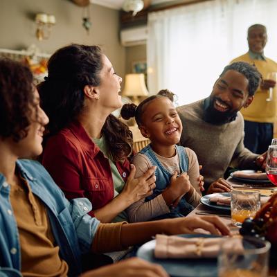 A big family laughing during Thanksgiving dinner at home.