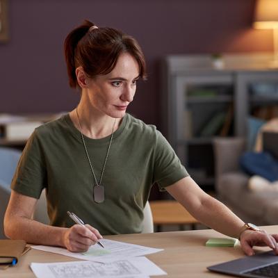 A young military woman browsing information using a laptop in an office.