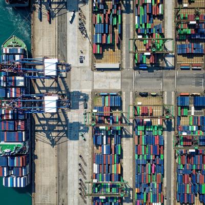 Aerial view on ships, cranes, and cargo containers by the quayside of a dock.