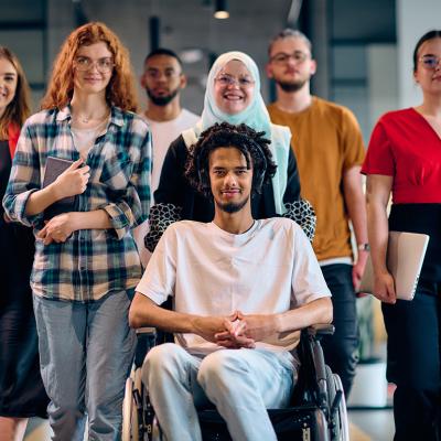 A diverse group of young business people, with a person in wheelchair at the center, showcasing community and accessibility.