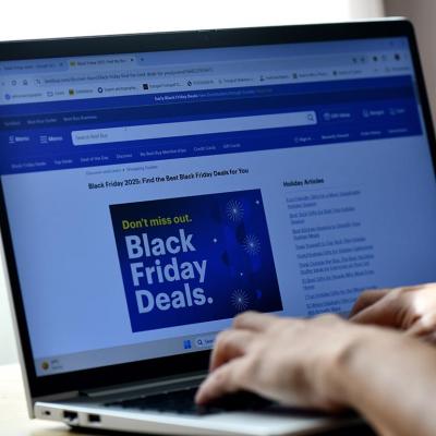 Hands typing on a laptop displaying a Black Friday Deals advertisement page.