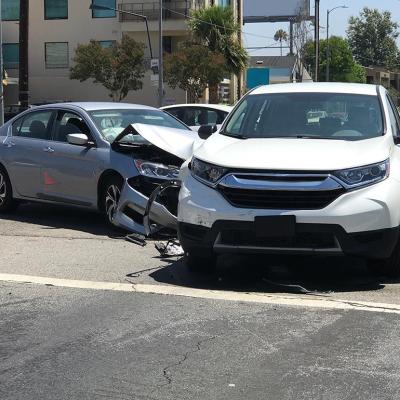 Two modern vehicles involved in a traffic accident are shown stopped in an intersection during the day in Los Angeles.
