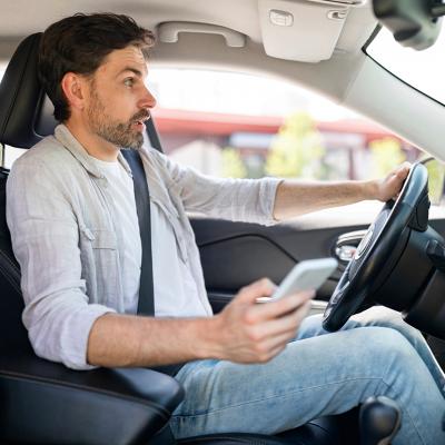 A male driver in shock as he is texting while driving.