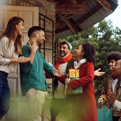 Young happy people greeting with a couple while arriving at their dinner party during winter holidays. 