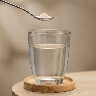 A spoon of Himalayan salt held above a glass of drinking water, highlighting its potential health benefits.