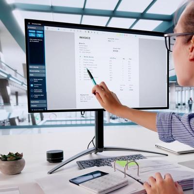 Person pointing out line item on invoice on large computer monitor.