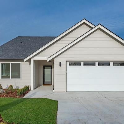 Middle class home exterior small rambler style house with simple style brand new construction blue sky green grass winter season family residence in a suburban neighborhood.