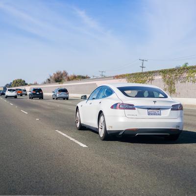 A white Tesla Model S driving on a freeway in San Francisco, California.