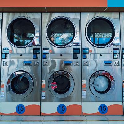 Rows of large industrial laundry machines in a laundromat.