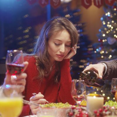 A young woman losing interest or appetite at a Christmas dinner table.