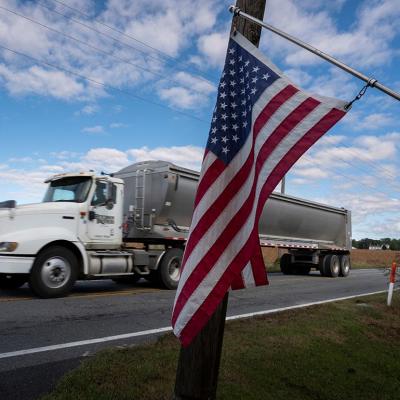 Travis Hutchison, a soybean farmer, drives his truck on a country road near his family's farm on a road behind an American Flag hanging, in Cordova, Maryland, on October 10, 2025.