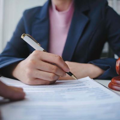 Torso of a female lawyer signing a document for a client in their office.