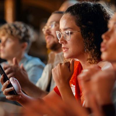 A female football fan in a bar monitoring game results on her phone.