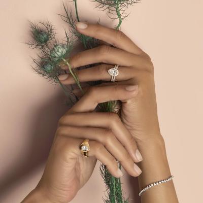 Hands of a bride holding flowers and showcasing diamond cut rings.