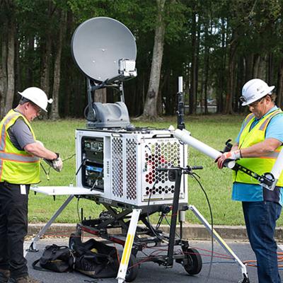 A technical staff setting up a portable satellite asset.