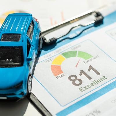 A mini figure of a blue car on top of a credit score report document.