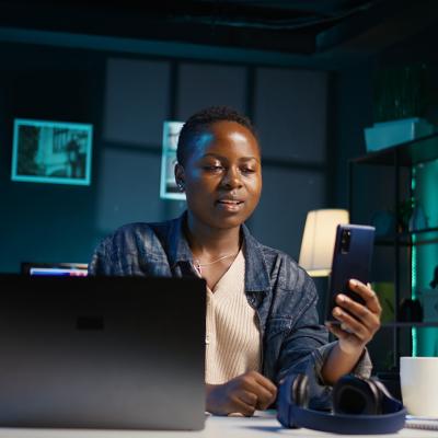 A black female professional answering a video call on her phone while working from home.