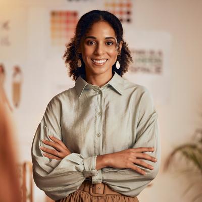 A black female fashion designer posing in her studio.