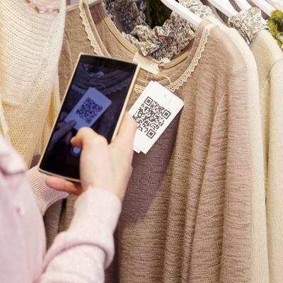 A woman scanning a clothing item's QR code on her phone.
