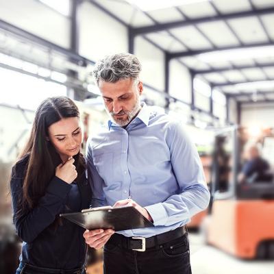 Warehouse manager and employee planning transport process in warehouse.