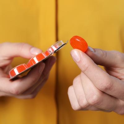A woman holding a red cough drop tablet.