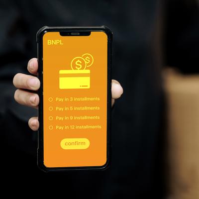 A person holding a smartphone displaying installment options for Buy Now, Pay Later method.