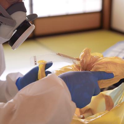 A crime scene cleanup worker in protective gear disposing garbage bags.