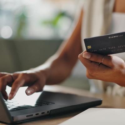 A female business professional typing credit card information for a purchase using her laptop.