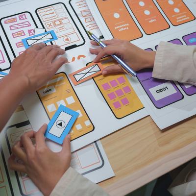 Web designers arranging cutouts to visualize a mobile app interface project.