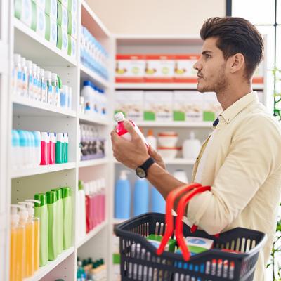 A man holding a basket and shopping at a pharmacy.