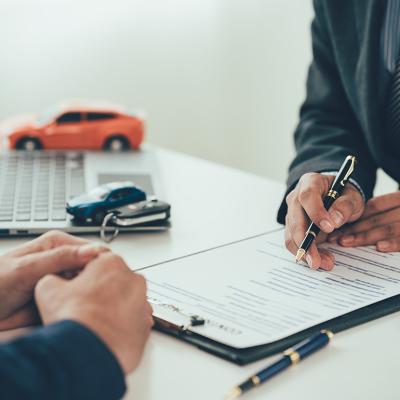 Figures of cars surround a table while a car salesperson transacts with a customer.