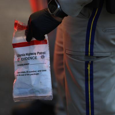 A California Highway Patrol officer holding an evidence bag after taking a suspect into custody.