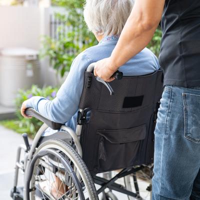 A caregiver caring for an elderly woman in a wheelchair.
