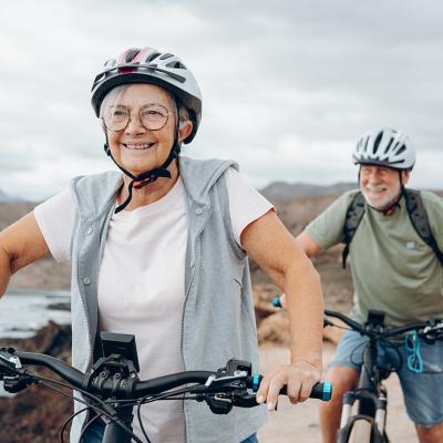 A senior couple riding their bikes on the beach.