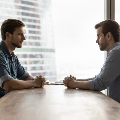 Two businessmen sitting across a table from each other engaged in discussion.