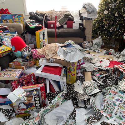 Piles of messy packaging and opened presents in a living room during Christmas morning.